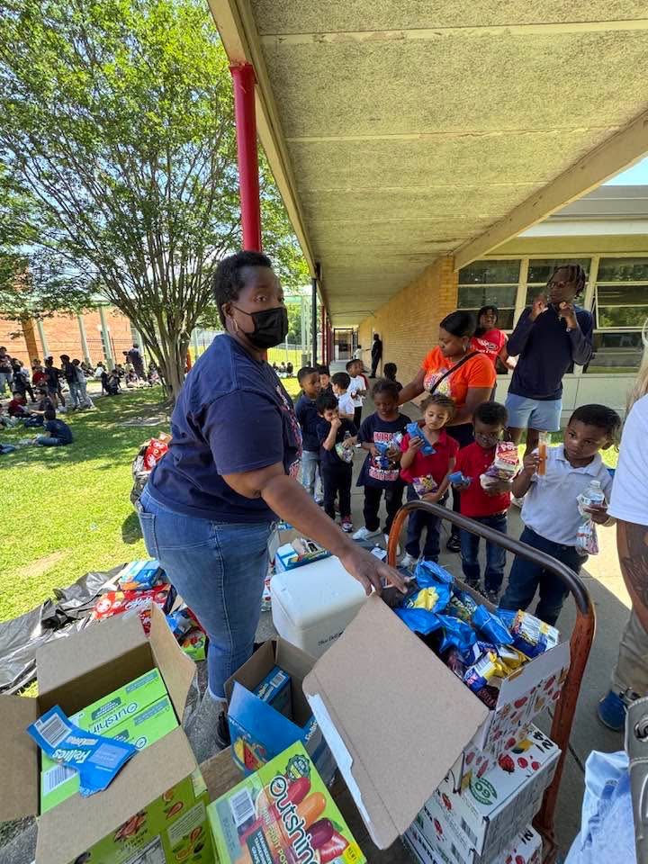 A volunteer handing out treats and water to students from a cart